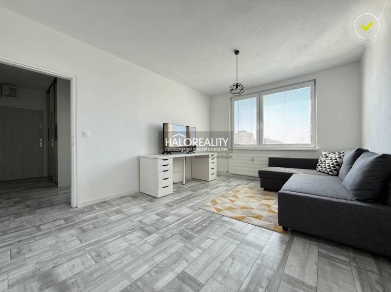 Nappali egy kétszobás lakásban, fa dekoros padlóval és szürke kanapéval.