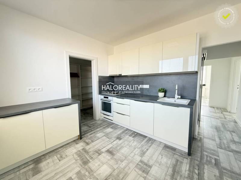 Konyha egy kétszobás lakásban fehér szekrényekkel és fa mintázatú padlóval.