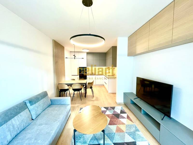 Nappali kanapéval, étkezőasztallal és TV-vel, fa dekorációjú padló, 2 szobás lakás.