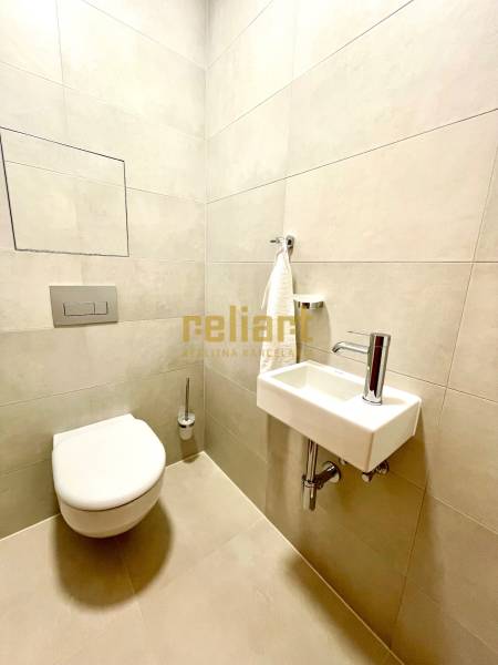 Fürdőszoba egy kétszobás lakásban WC-vel, mosdóval és világos csempékkel.