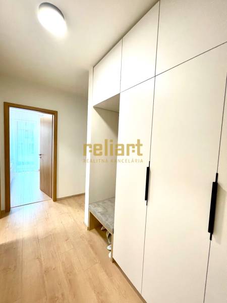 Két szobás lakás folyosója fehér szekrénnyel és fa mintázatú padlóval.