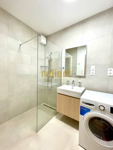 Fürdőszoba zuhanyzóval és mosógéppel egy kétszobás lakásban.