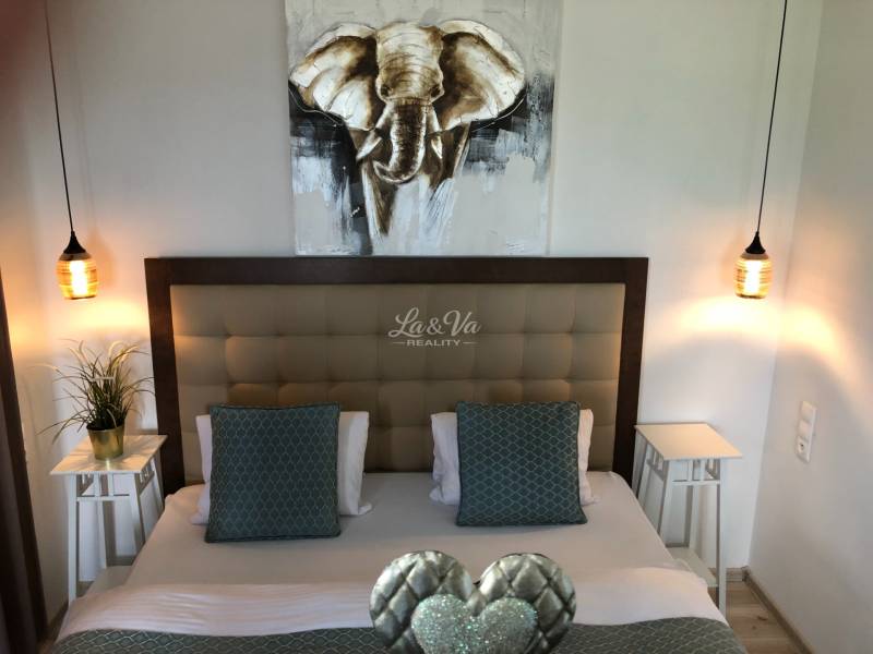 Hálószoba stílusos világítással és elefántképpel egy kétszobás lakásban.