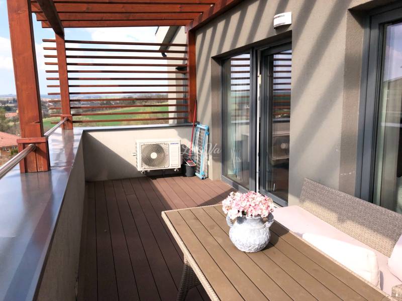 Kétszobás lakás terasza kilátással a környékre és virágdíszítéssel.