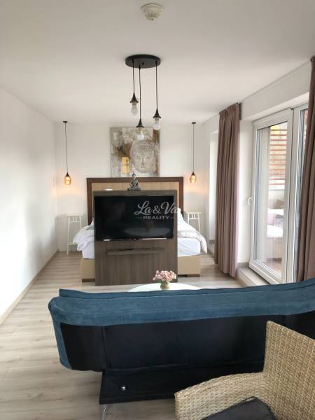 Nappali egy kétszobás lakásban fa dekor padlóval és külön hálószobás zónával.