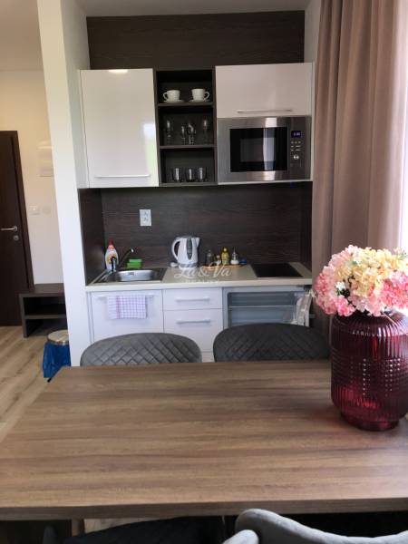 Konyha egy kétszobás lakásban fehér szekrényekkel és mikrohullámú sütővel.