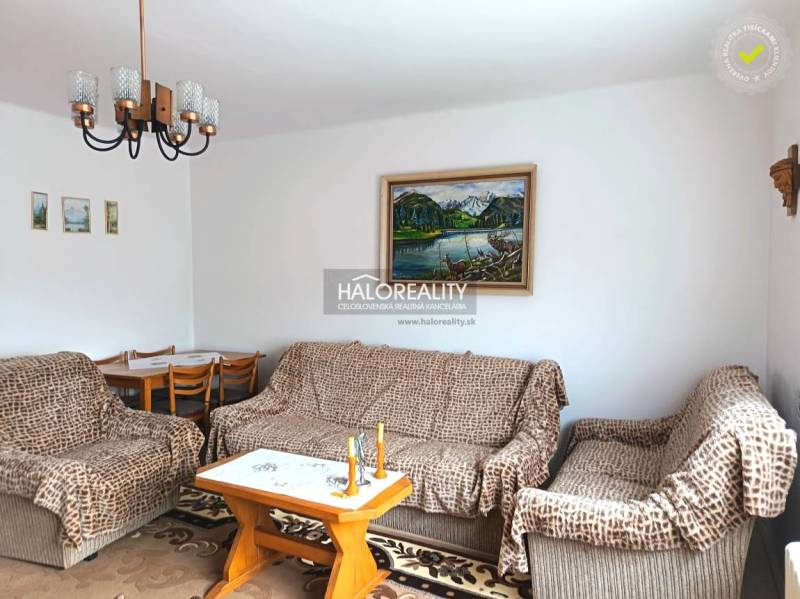 Családi ház nappalija kanapéval, képpel és étkezőasztallal.