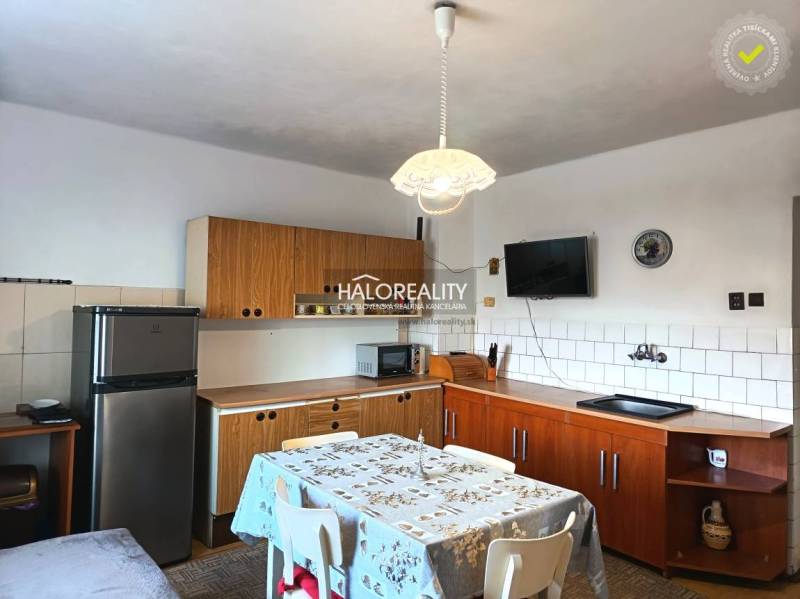 Konyha családi házban fa konyhabútorral és étkezőasztallal.