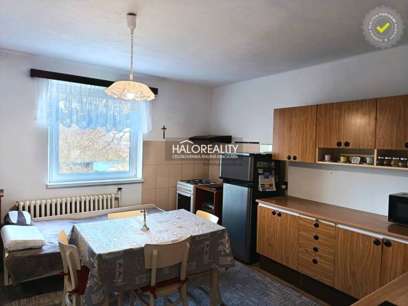 Családi ház konyhája étkezőasztallal és fa szekrényekkel.