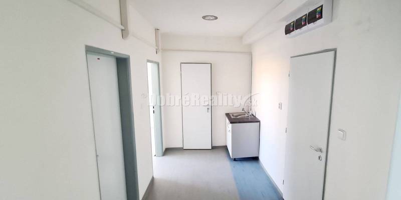 Irodák mosdóval és ajtókkal, fa dekorációjú padló, fehér falak.