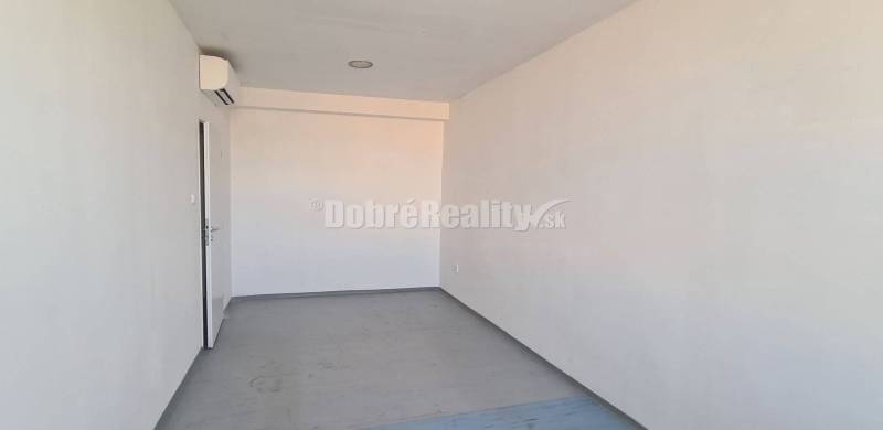 Svetlé kancelárske priestory fehér falakkal és ablakkal, fa mintázatú padlóval.