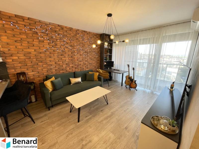 Nappali egy kétszobás lakásban téglaburkolattal és fa dekoros padlóval.