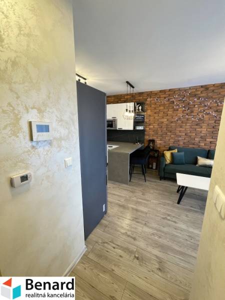 2 szobás lakás belső tere fa dekor padlóval, téglafallal és konyhasarokkal.