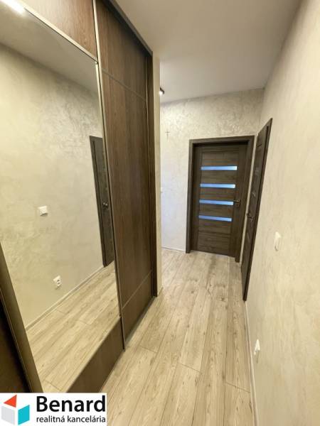 Folyosó fa dekor padlóval, beépített szekrénnyel és ajtókkal egy kétszobás lakásban.