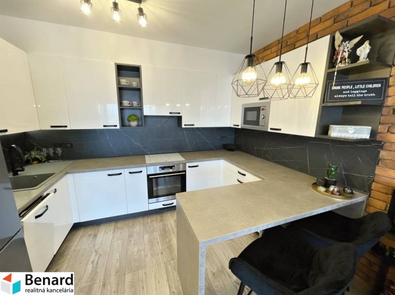 Konyha egy kétszobás lakásban fehér szekrényekkel és fa mintázatú padlóval.