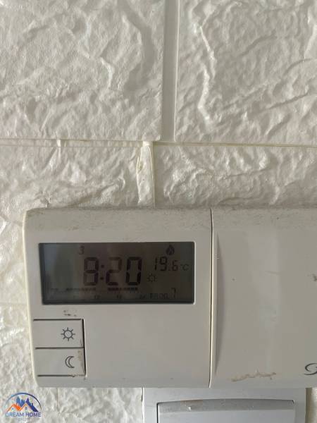 Hőmérsékletszabályozó a fehér falon egy háromszobás lakásban, 19,6 °C-ot mutat.
