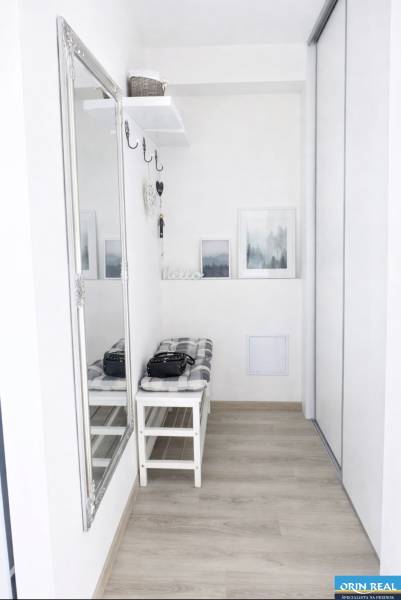 Előszoba egy kétszobás lakásban tükörrel, paddal és fa dekorációjú padlóval.