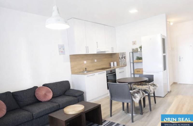 Nappali konyhával egy kétszobás lakásban, fa dekorációjú padlóval.