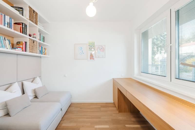 Világos szoba fa mintás padlóval, kanapéval és nagy ablakokkal.