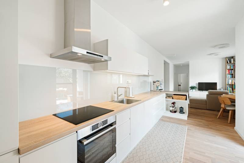 Konyha egy 4 szobás lakásban, fa dekoros padlóval és világos berendezéssel.