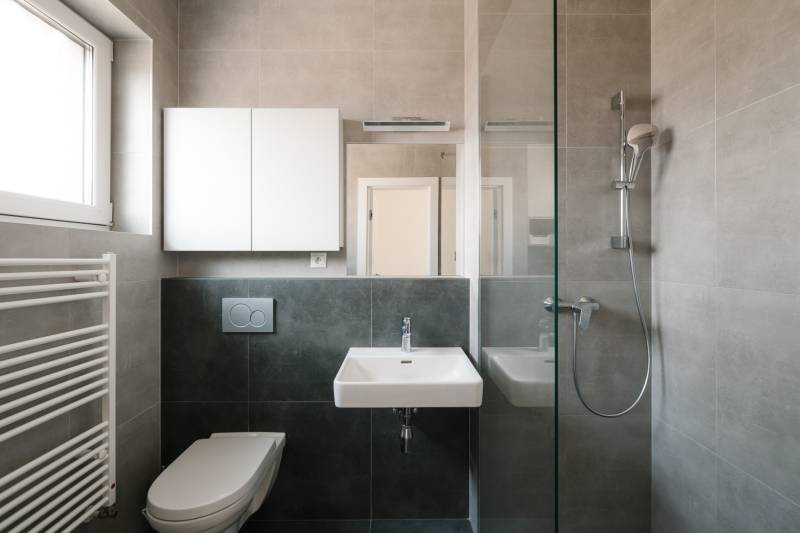 Négy szobás lakás fürdőszobája mosdóval, zuhanyzóval, WC-vel és szekrénnyel.