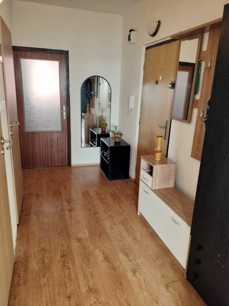 3 szobás lakás folyosója fa dekor padlóval és akasztós fallal.