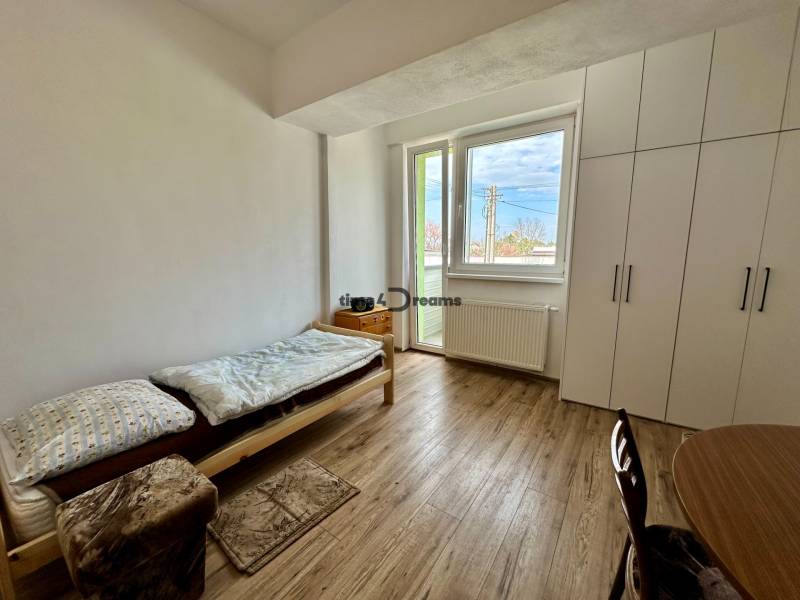 Garzonlakás ággyal, asztallal, szekrénnyel és fa dekor padlóval.