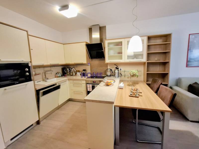 Konyha egy kétszobás lakásban étkezőasztallal és fa dekoros padlóval.