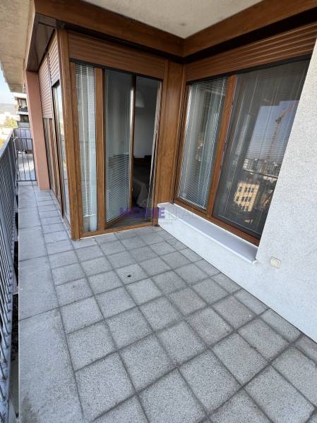 Erkély csempével és fa dekorációval, egy 2 szobás lakás része, korláttal és kilátással.