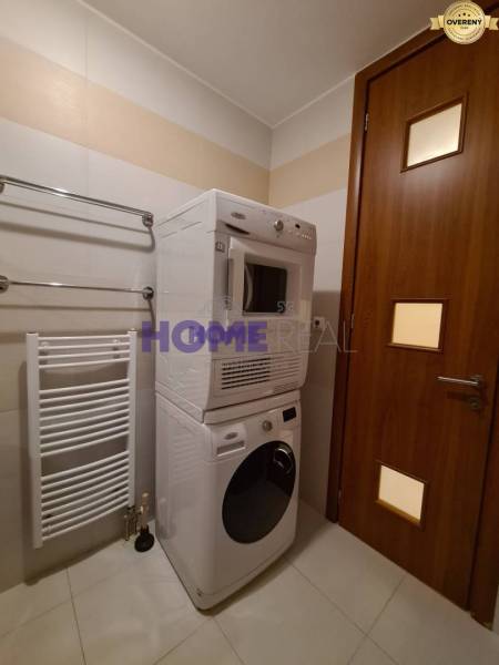 Fürdőszoba egy kétszobás lakásban mosógéppel és szárítógéppel, fehér radiátor a falon.