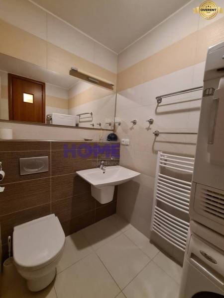 Fürdőszoba egy kétszobás lakásban WC-vel, mosdóval és fehér létra radiátorral.