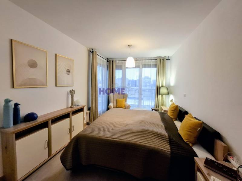 Hálószoba ággyal, dekoratív párnákkal és komóddal egy kétszobás lakásban.