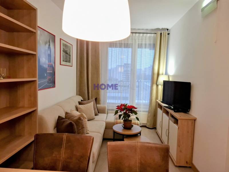 Obývacia izba v 2-izbovom byte s pohodlnou sedačkou a policami.