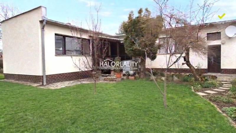 Családi ház Poltáron kerttel és fákkal, rendezett gyep.