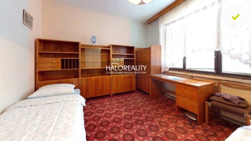 Szoba szőnyegpadlóval, fa bútorokkal egy családi házban.