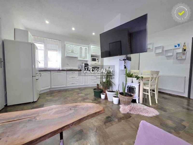 Konyha családi házban fehér bútorokkal, dekoratív növényekkel és fa dekoros padlóval.