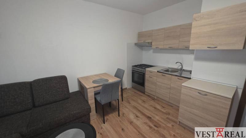 Konyha egy egyszobás lakásban fa dekorációjú padlóval és bútorokkal.