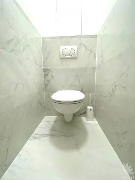 Fürdőszoba függesztett WC-vel és márvány burkolattal egy kétszobás lakásban.
