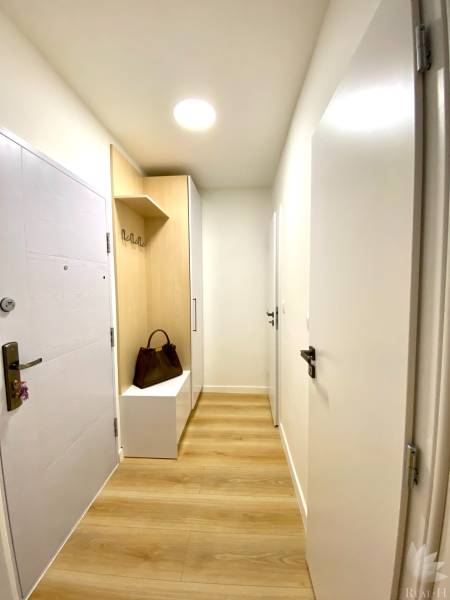 Előszoba fa dekor padlóval, szekrénnyel és fogassal egy kétszobás lakásban.