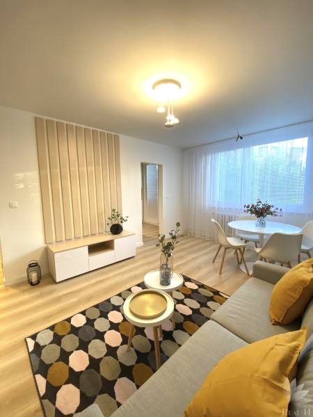 Nappali egy kétszobás lakásban, fa dekorációjú padlóval, világos bútorokkal és dekorációkkal.