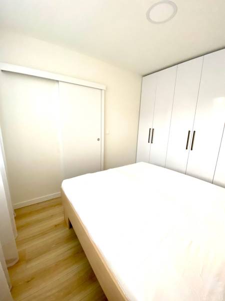 Hálószoba egy kétszobás lakásban, ággyal és nagy beépített szekrénnyel.