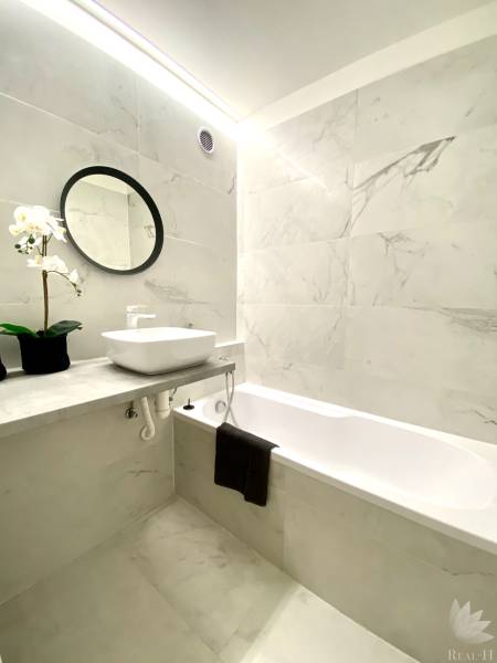 Fürdőszoba egy kétszobás lakásban káddal, tükörrel és virágdekorációval.