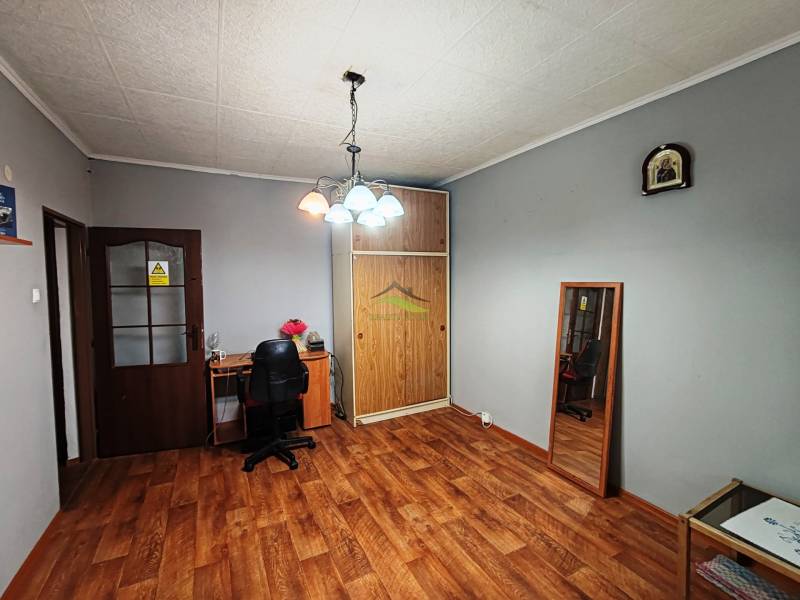 Szoba egy négy szobás lakásban fa dekor padlóval és íróasztallal.