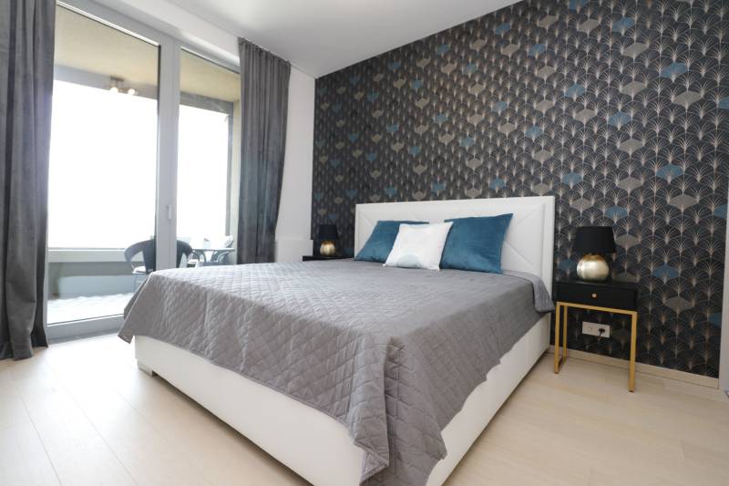 Hálószoba ággyal, tapétával és erkéllyel a kétszobás lakásban.