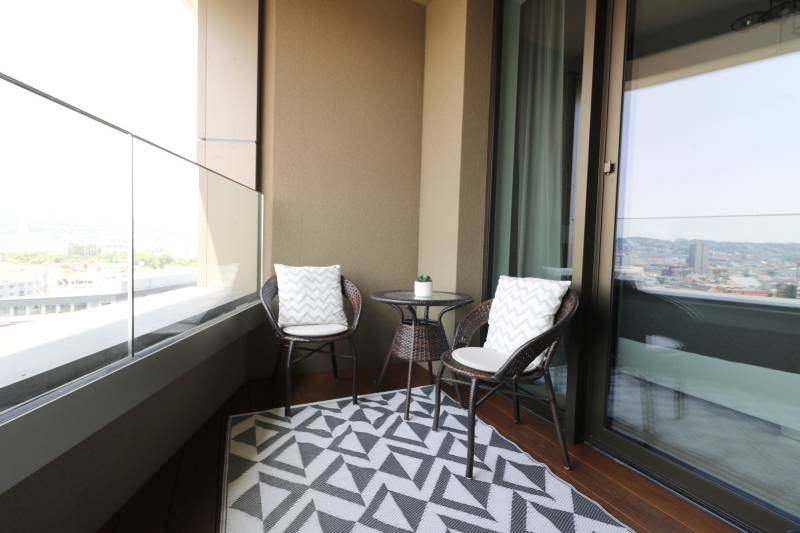 Erkély egy 2 szobás lakásban rattan bútorokkal és kilátással a városra.