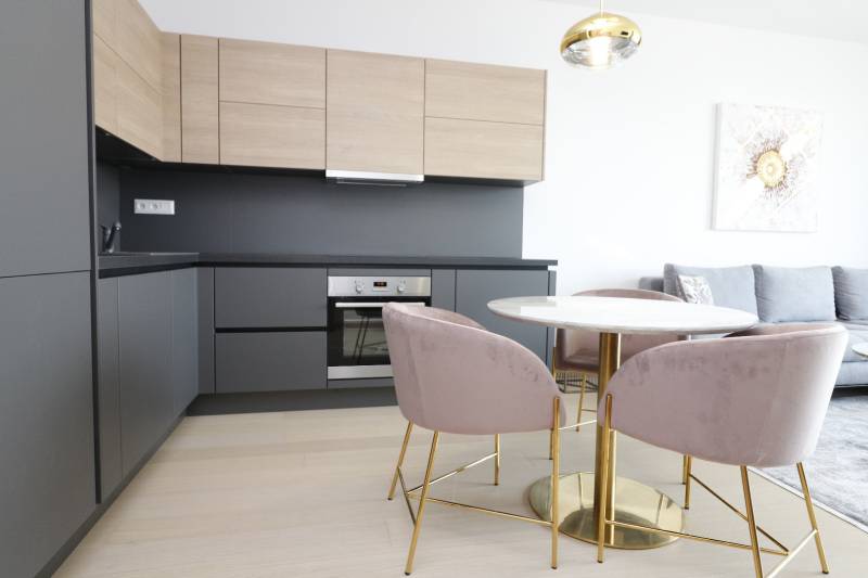 Két szobás lakás konyhája fa mintázatú padlóval és stílusos asztallal.