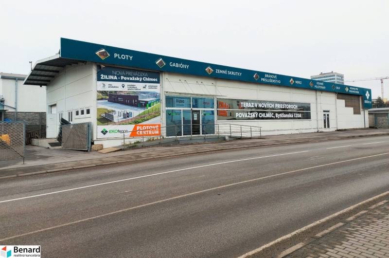 Üzlethelyiségek a Kő utcában, Zsolnán, reklámfeliratokkal és üres parkolóval.