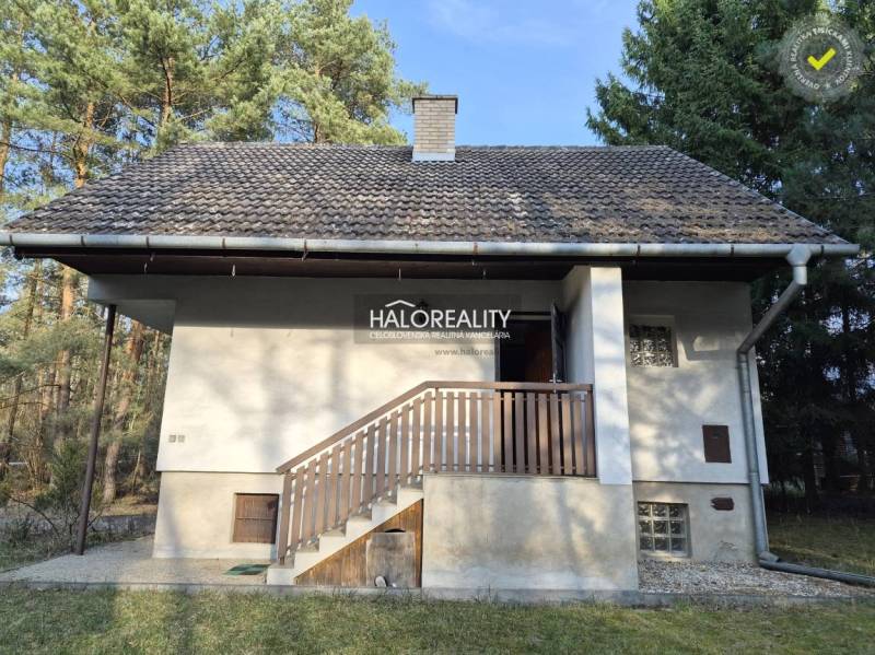 Házikó Borsky Svätý Jurban az erdő közepén, erkéllyel és ferde tetővel.