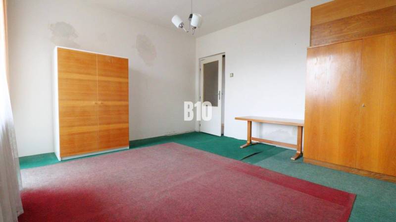 Szoba családi házban, szőnyegekkel, két szekrénnyel és egy asztallal.