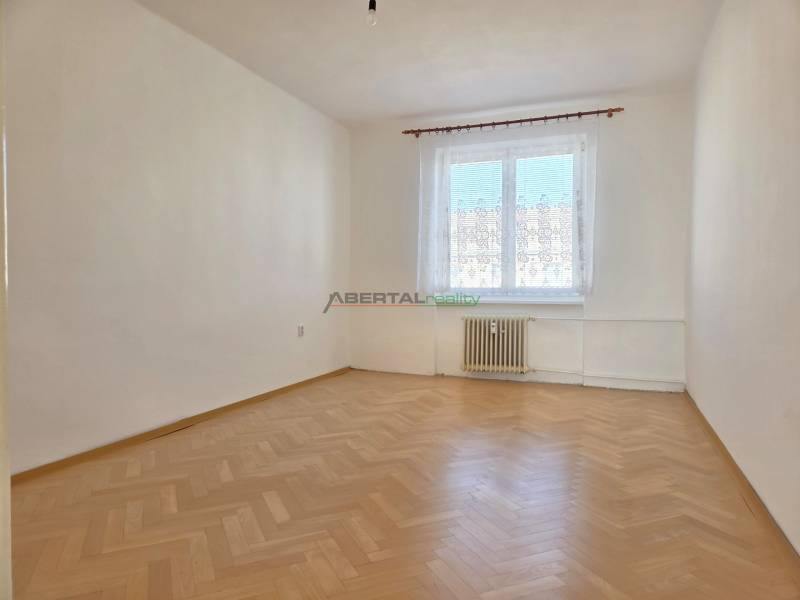 Üres szoba ablakkal és fa dekorációjú padlóval egy háromszobás lakásban.